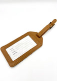 Brown leather luggage tag with a white label on a white background