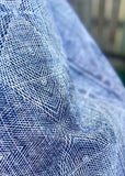 Close-up of a black, brown, grey and white garment with a fine grid pattern, shown in soft folds against a blurred background.